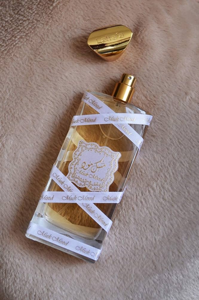 Frasco de perfume transparente com detalhes dourados sobre tecido rosa claro