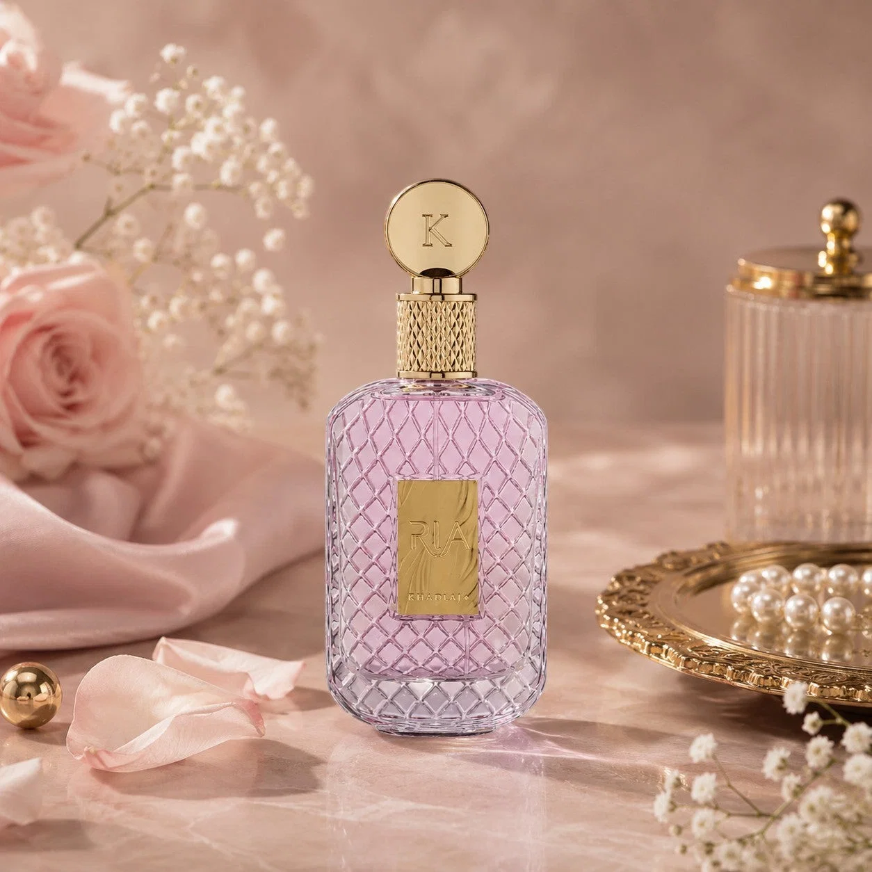 Frasco de perfume rosa claro com tampa dourada e flores ao redor