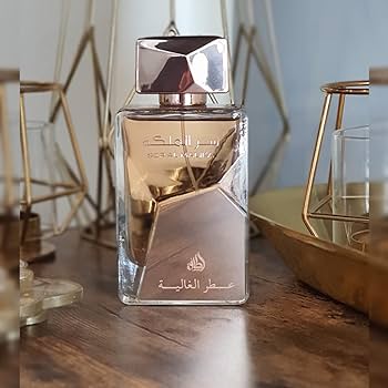 Frasco de perfume dourado com texto em árabe sobre mesa de madeira