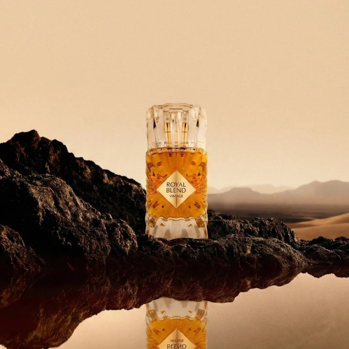 Frasco de perfume Royal Blend vintage em vidro facetado sobre rocha num ambiente desértico.