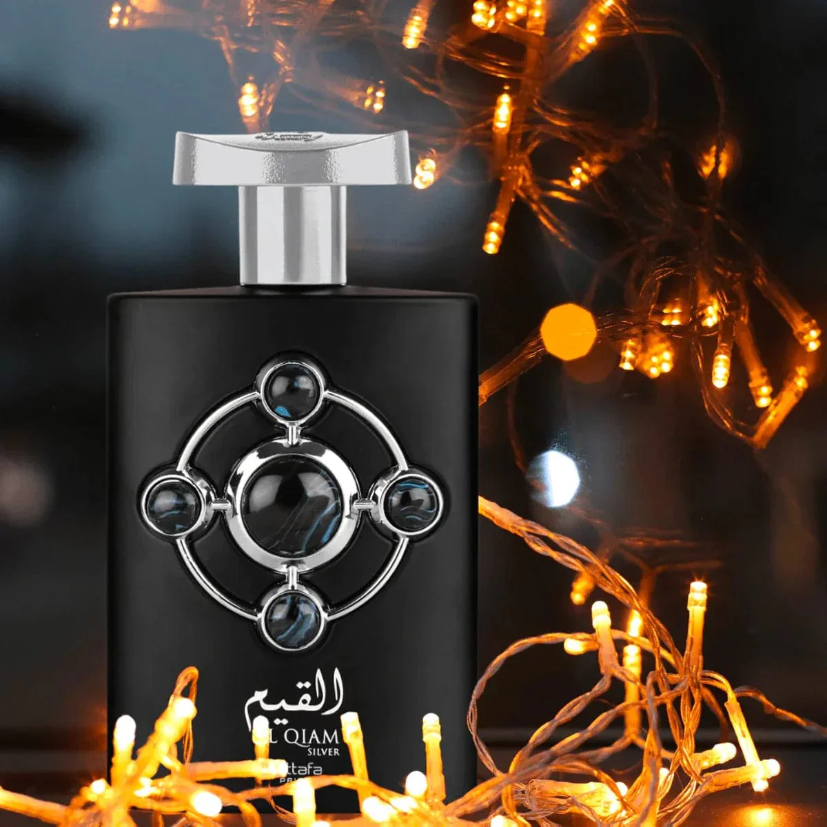 Frasco de perfume preto com design prateado e luzes decorativas amarelas