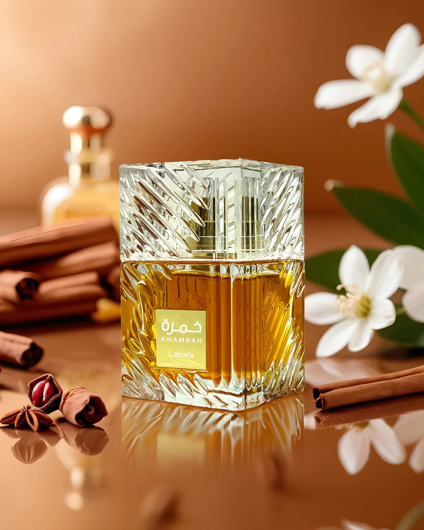 Frasco de perfume dourado e transparente com paus de canela e flores brancas