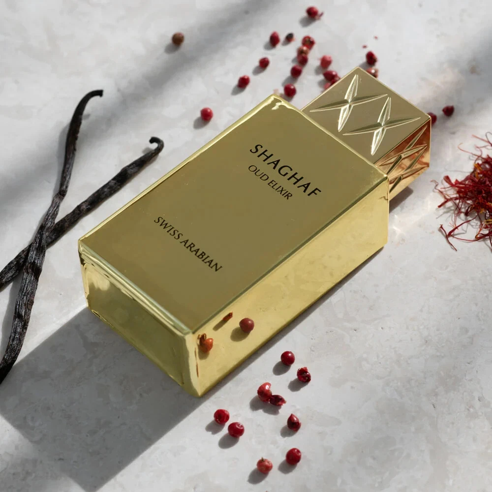 Frasco dourado de perfume SHAGHAF OUD EXIR SWISS ARABIAN com especiarias ao redor