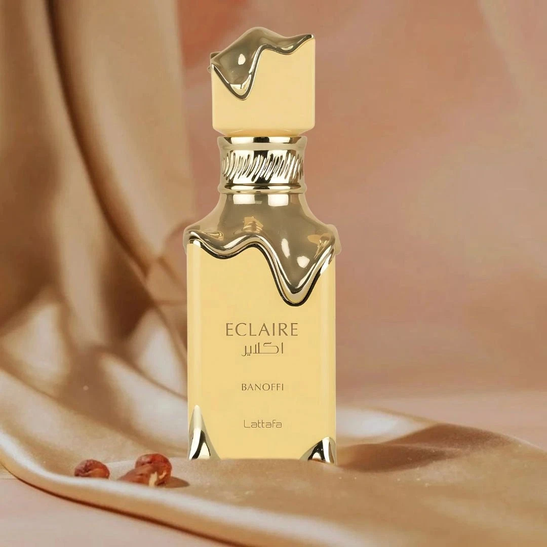 Frasco dourado de perfume ECLAIRE BANOFFI Lattafa sobre tecido bege.