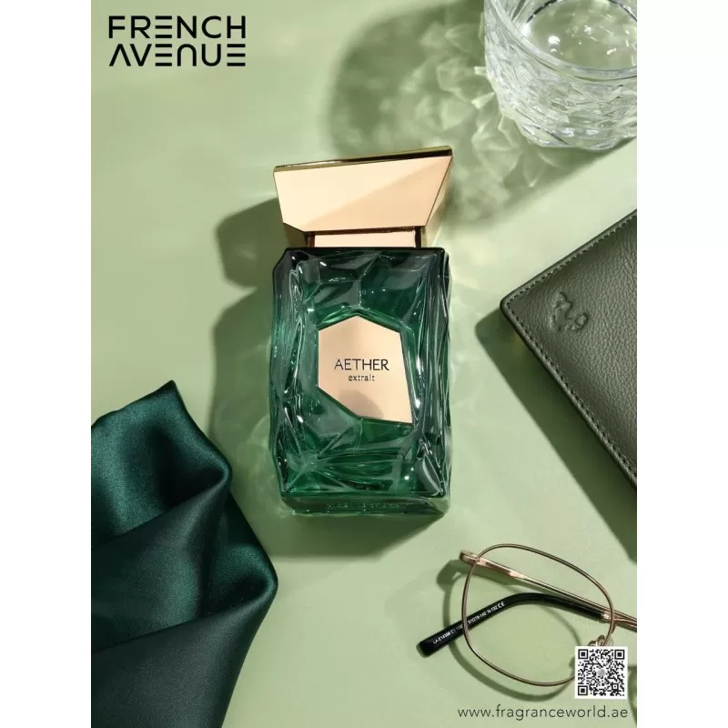 Frasco de perfume AETHER French Avenue em vidro verde com tampa dourada sobre superfície verde clara com acessórios