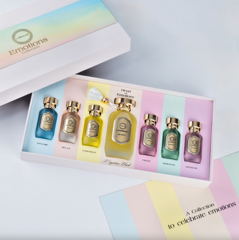 Conjunto de frascos de perfume coloridos em caixa branca com tampa colorida e texto Emotions Collection