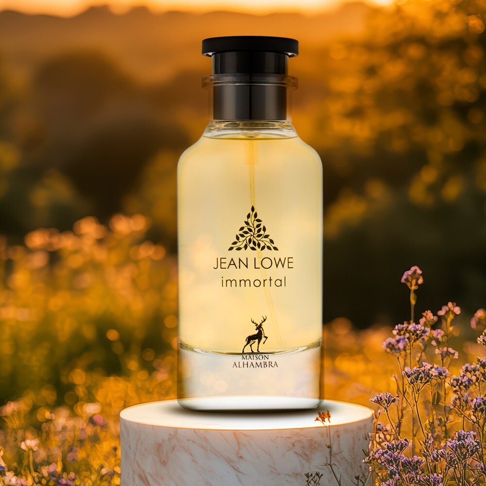 Frasco de perfume Jean Lowe Immortal em vidro com tampa preta sobre base branca e flores num campo ao pôr do sol