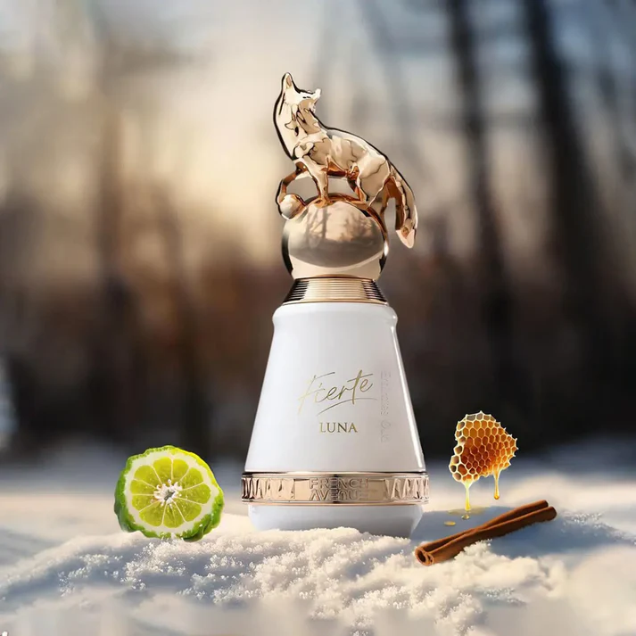Frasco de perfume LUNA com tampa dourada em forma de lobo na neve, com limão, favo de mel e canela ao lado.