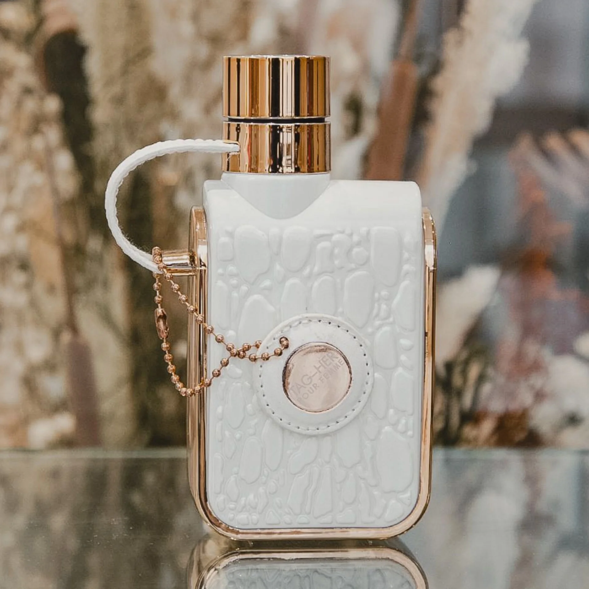 Frasco de perfume branco com detalhes dourados e textura de pele de crocodilo