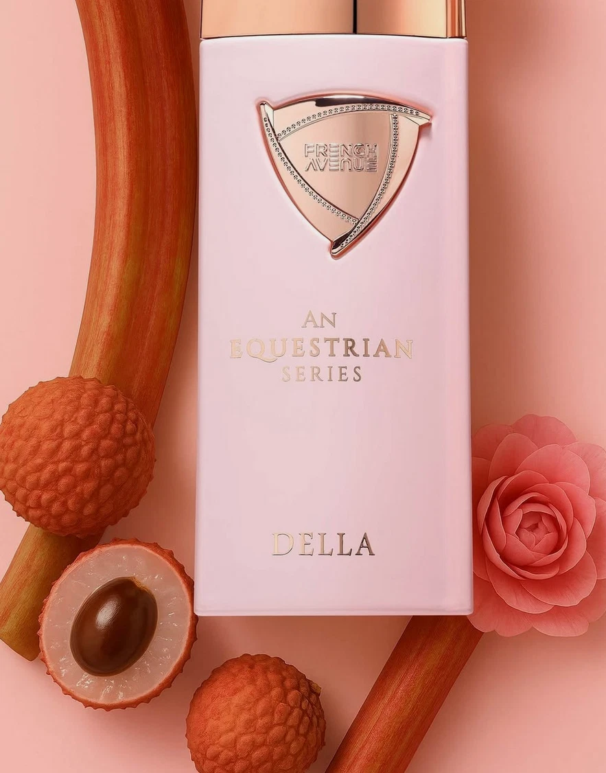 Frasco de perfume rosa claro com inscrições douradas rodeado por lichias e flores cor-de-rosa.