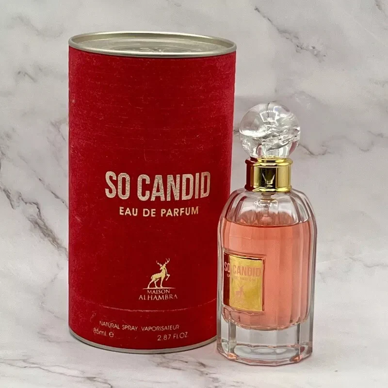 Frasco de perfume So Candid ao lado de embalagem cilíndrica vermelha