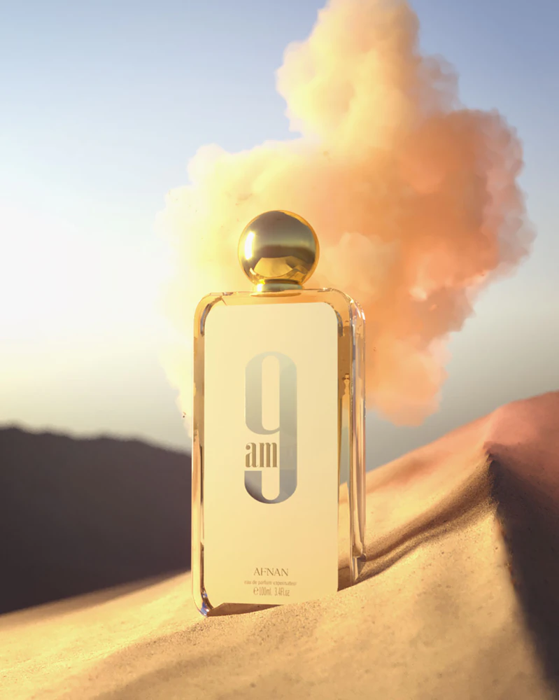 Garrafa de perfume transparente com tampa dourada e texto '9 am AYNAN'