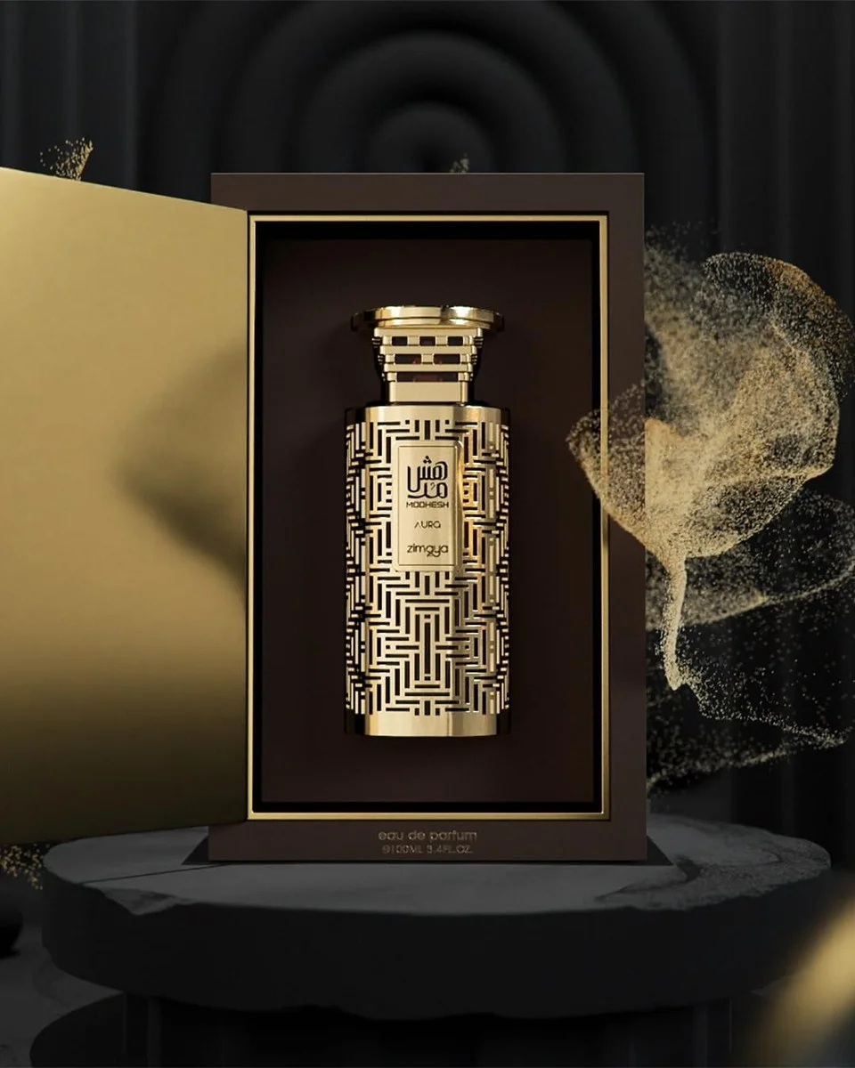 Frasco de perfume dourado decorado dentro de caixa preta com interior dourado e texto visível.