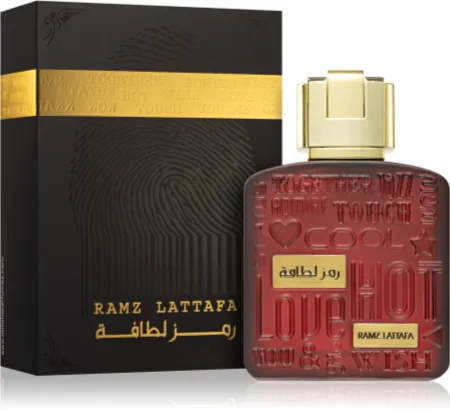 Perfume Ramz Lattafa com frasco vermelho e tampa dourada junto a embalagem preta com faixa dourada