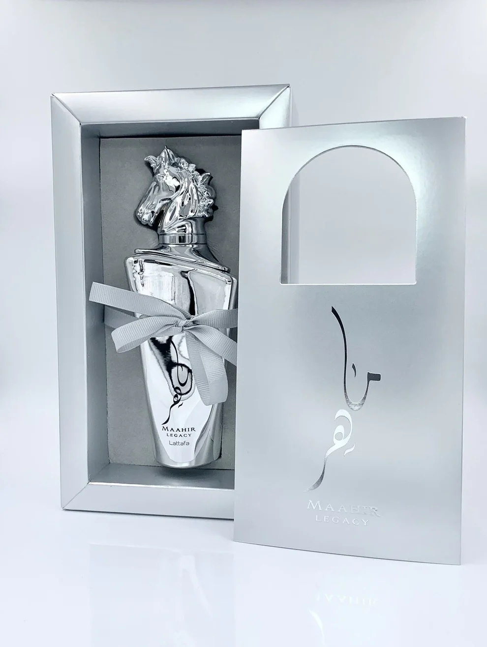 Frasco de perfume prateado em embalagem prateada com laço cinzento