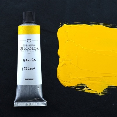 Tubo de tinta amarela e amostra de tinta sobre fundo preto.