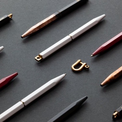 Várias canetas coloridas e peça metálica sobre fundo escuro