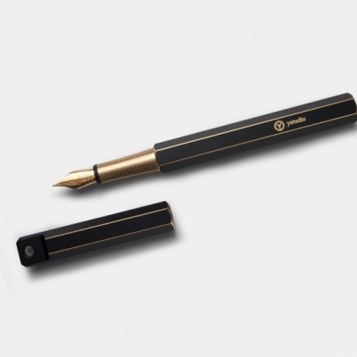 Caneta preta com detalhes dourados e tampa removível em fundo branco