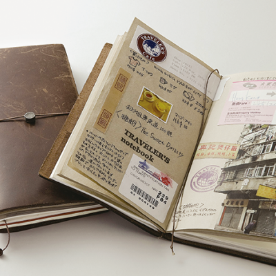 cadernos de viagem abertos e fechados em couro castanho com decorações e textos nas páginas abertas