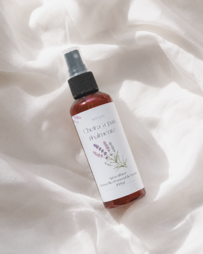 Spray difusor Aroma Óleo Essencial de Lavanda 100ml em frasco âmbar com rótulo branco e tampa preta, sobre tecido branco.