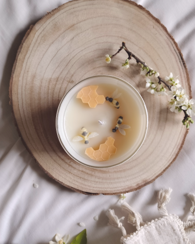 Vela aromática com decoração de abelhas e favo de mel sobre disco de madeira
