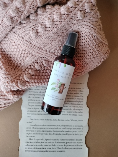 Frasco de spray difusor com rótulo branco sobre página de livro e manta rosa de malha