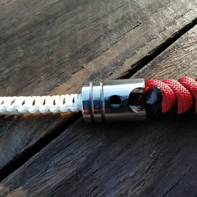 Cordas branca e vermelha entrelaçadas presas a peça metálica sobre madeira