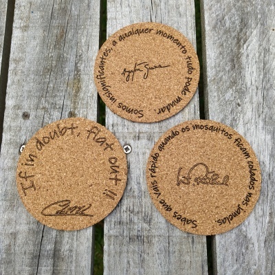 Três discos redondos de cortiça com textos em preto sobre uma superfície de madeira.
