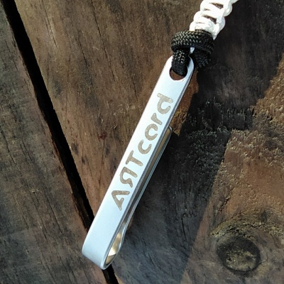 Colar com pendente metálico prateado gravado com palavra ARTCCCK e cordões trançados branco e preto