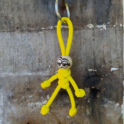 Porta-chaves boneco de corda amarela e cabeça branca com rosto desenhado