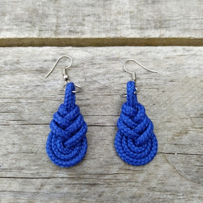 Brincos de corda azul trançada com ganchos metálicos sobre madeira cinzenta