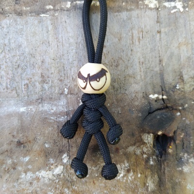 Boneco de corda preta com cabeça de madeira pintada e expressão zangada