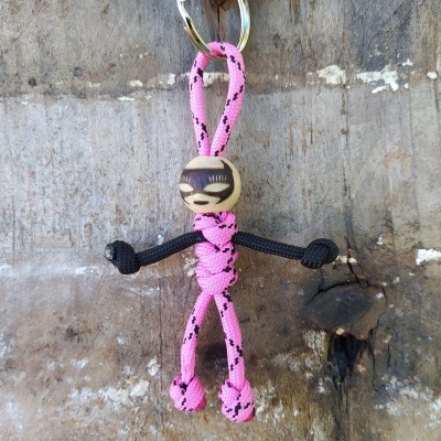 Porta-chaves com figura humana feita de corda rosa e preta e cabeça de madeira