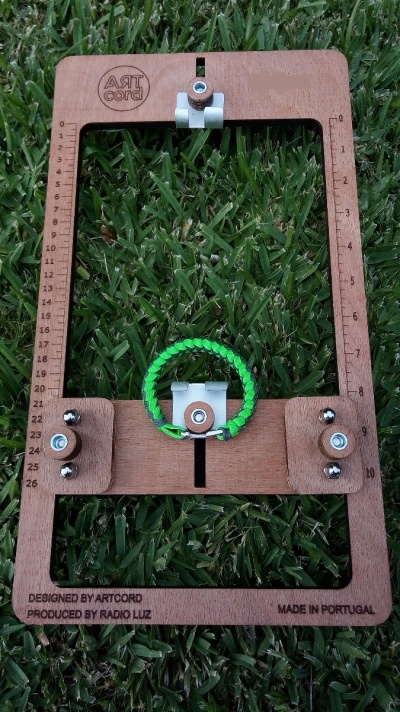 moldura de madeira ART cord com pulseira verde e ajustes metálicos sobre relva