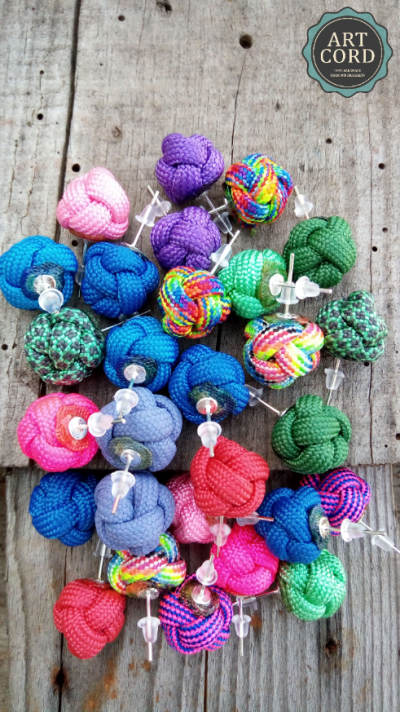 Brincos de nós de corda coloridos sobre madeira com etiqueta ART CORD