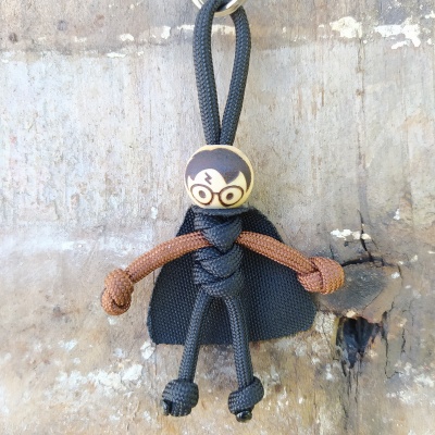 Boneco de corda com capa preta pendurado numa parede de madeira