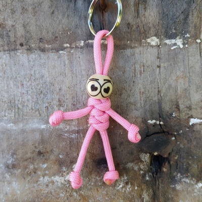 Chaveiro boneco de corda rosa com cabeça de madeira e olhos em forma de coração