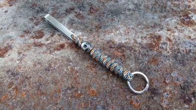 porta-chaves de metal com conta e presilha sobre superfície enferrujada