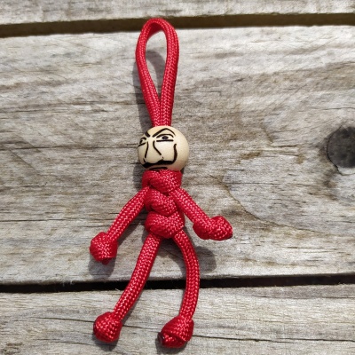 Chaveiro de cordão vermelho com conta de madeira pintada, sobre madeira clara