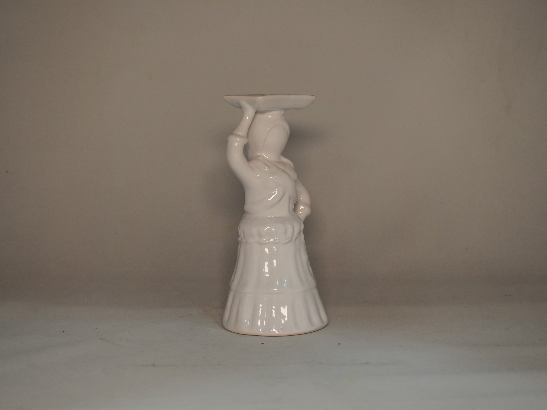 Peça decorativa em cerâmica branca representando figura feminina com prato