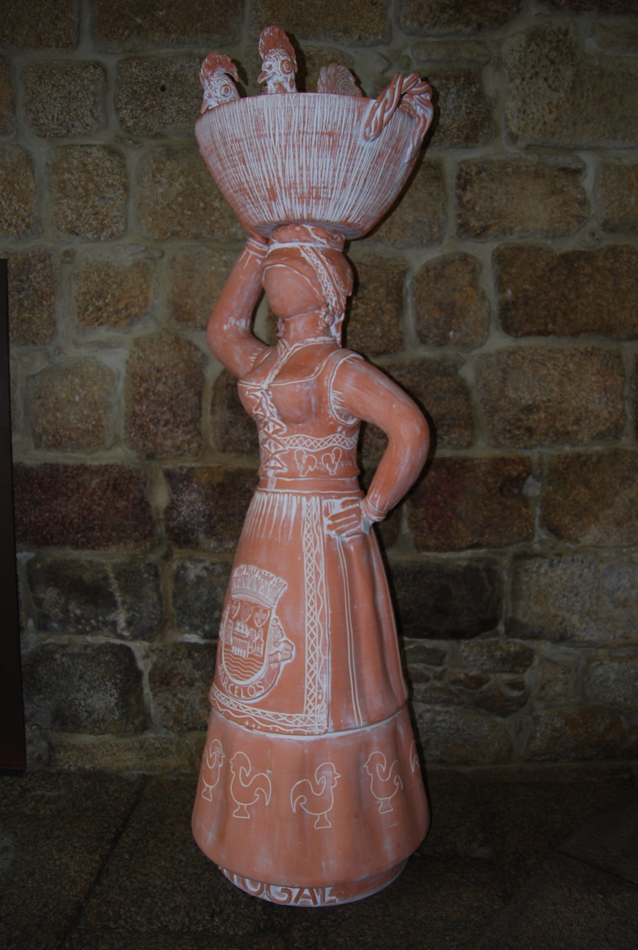 Escultura em terracota de mulher com cesta na cabeça e vestido decorado com galinhas