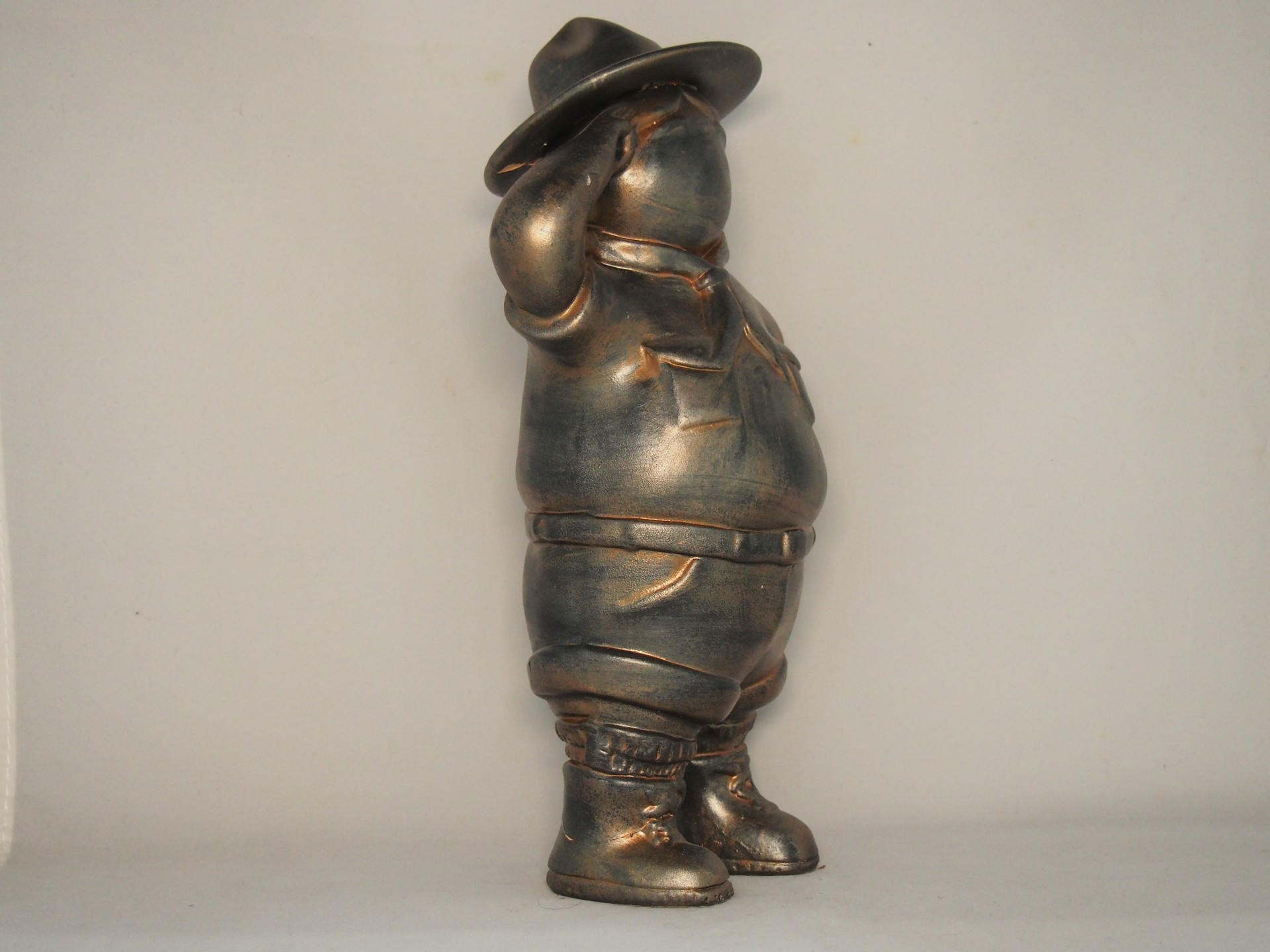 Escultura de metal bronzeado de um boneco com chapéu e lenço