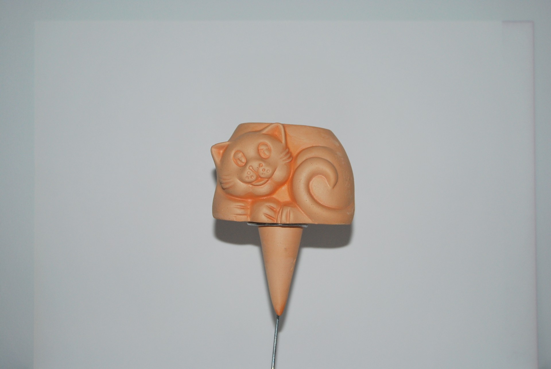 Regador de plástico laranja em forma de gato com fundo branco