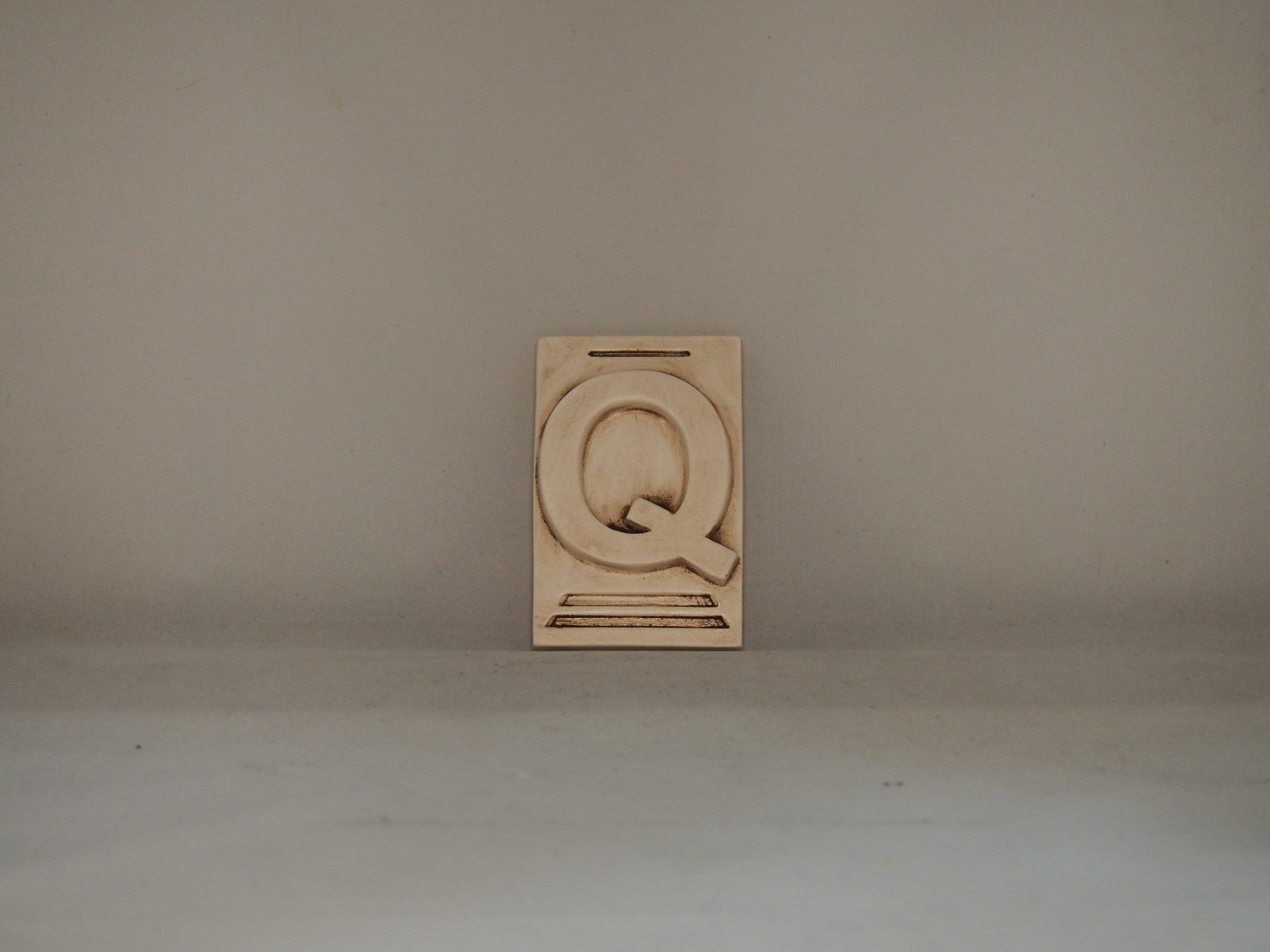 Placa de madeira com a letra Q em relevo