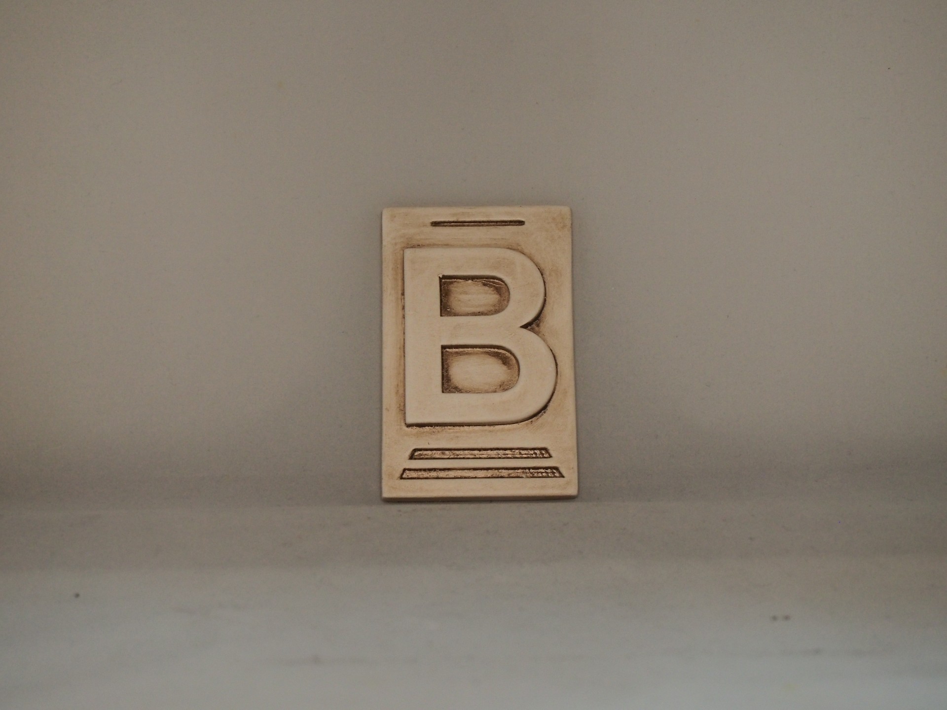 Placa decorativa de madeira com a letra B em relevo