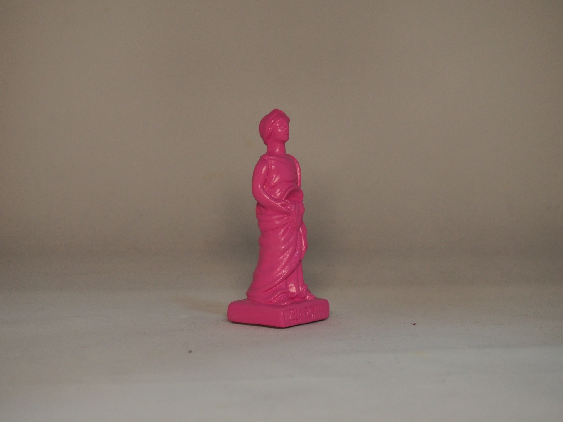Estatueta rosa de figura humana em fundo neutro