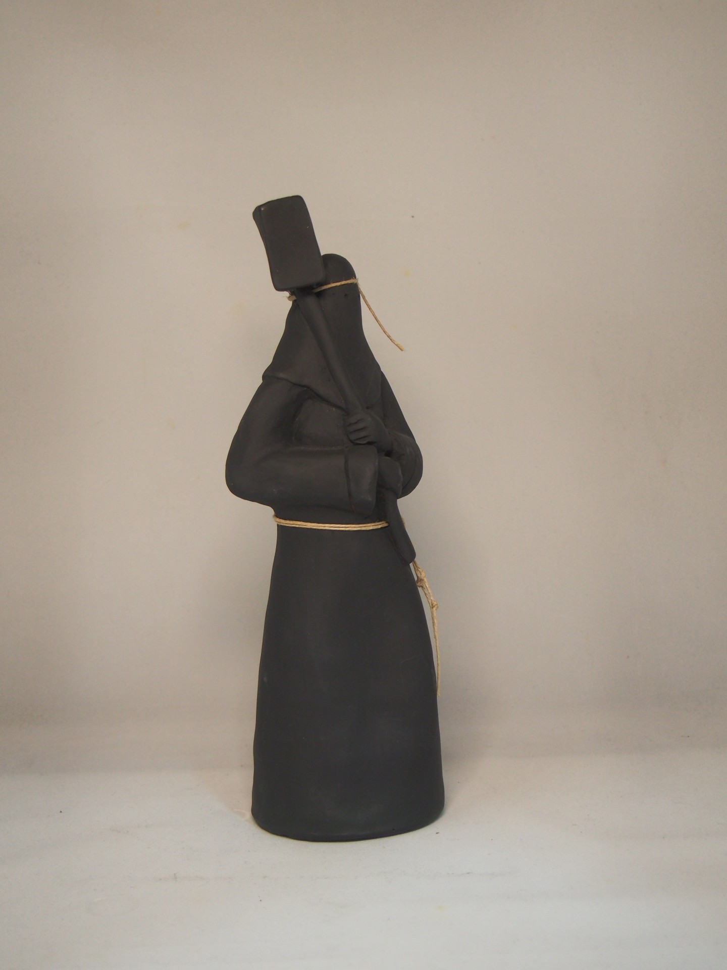 Estátua decorativa vestida de preto segura bastão em fundo branco