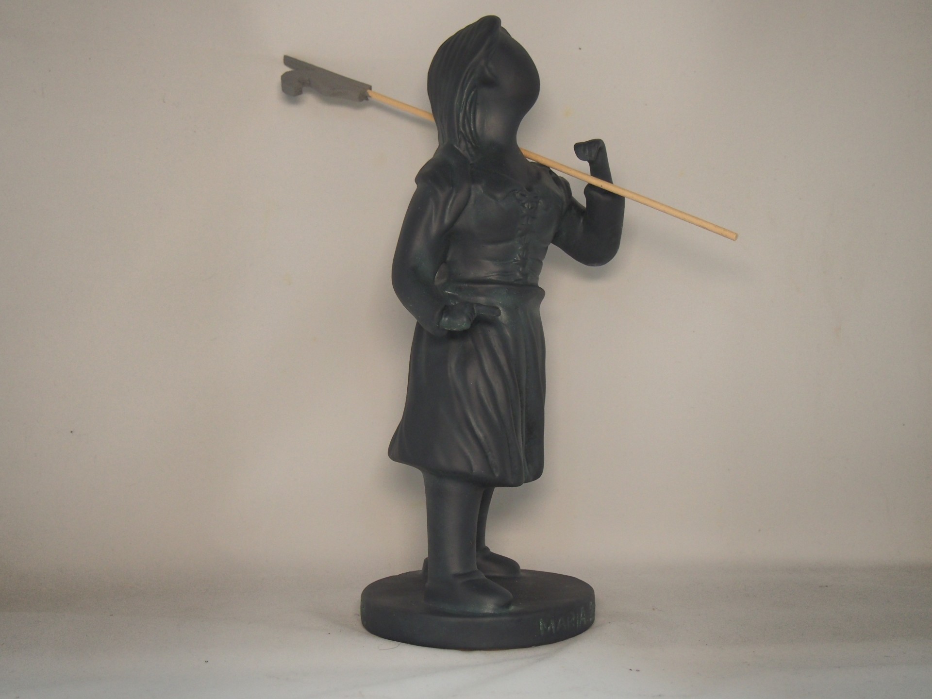 Estátua preta de figura com capuz e túnica segurando bastão