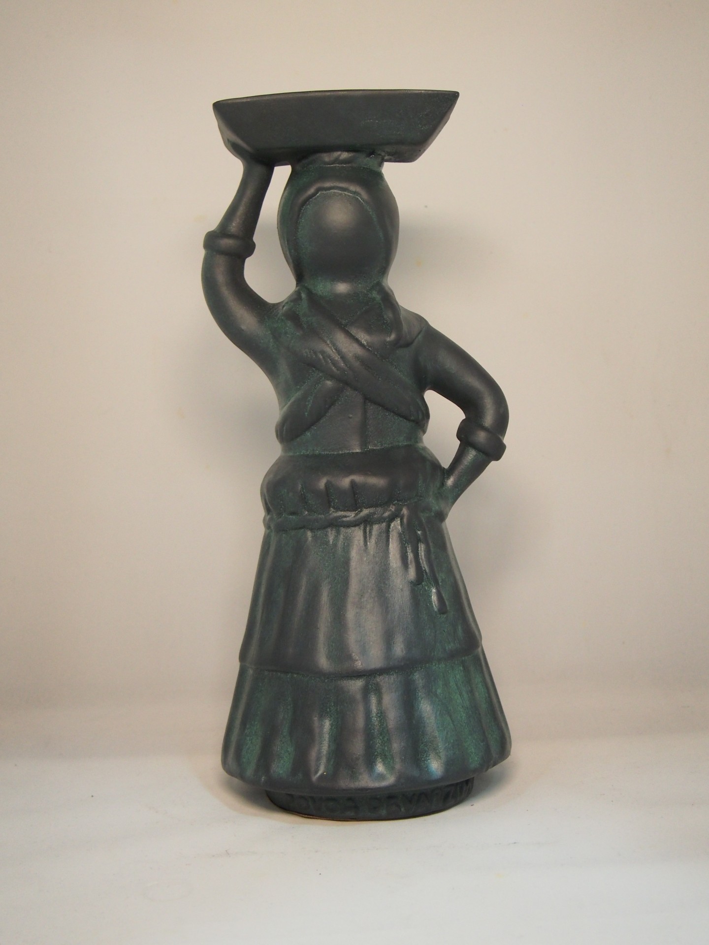 Escultura decorativa de mulher segurando bandeja na cabeça, em tons de verde e preto