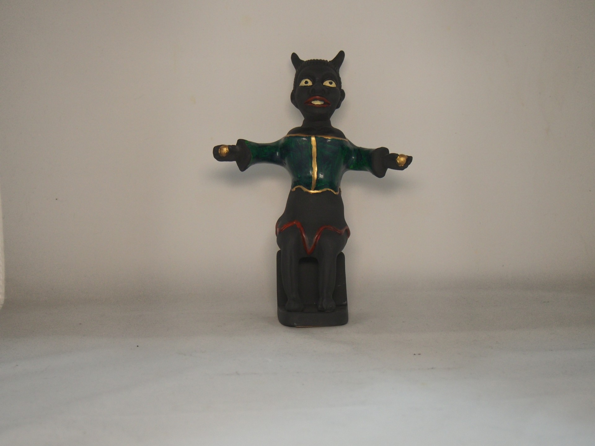 Figura decorativa de gato preto sentado com roupa verde e detalhes dourados